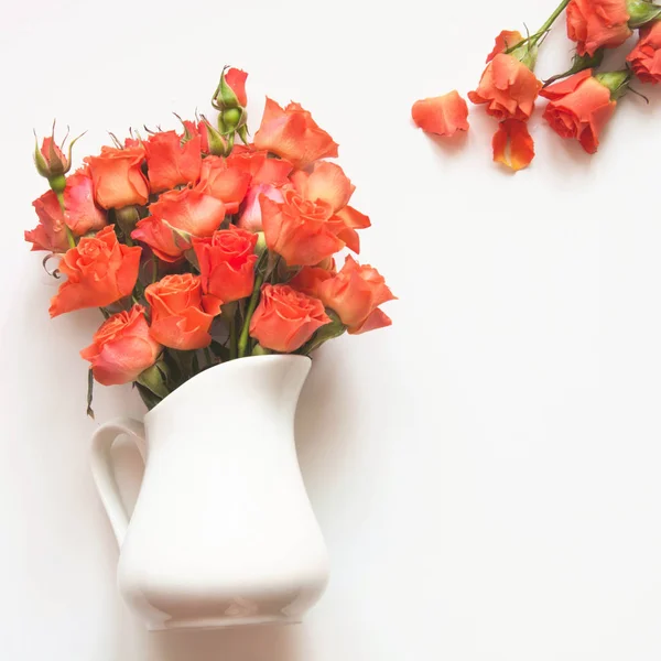 Orange roses in vase on white background. Spring concept. Top view. Floral pattern. Matte.