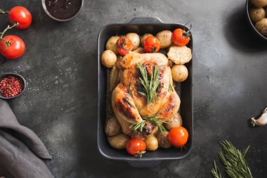 Patates ile kavrulmuş tavuk, domates siyah masada. Yukarıdan görüntülemek.