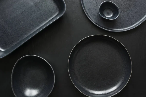 Посуд, глиняний посуд, чорний посуд і різні речі на чорній стільниці. Вид зверху . — стокове фото