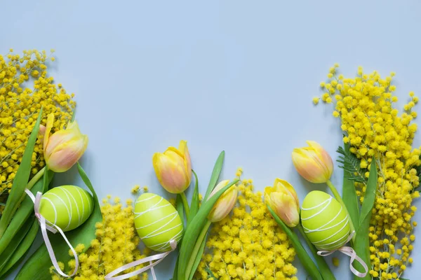 Borde de Pascua y primavera de tulipanes amarillos, mimosa sobre azul. Vista superior con espacio de copia . — Foto de Stock