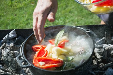 Shurpa çorba büyük bir demir döküm kazan açık. Yemek. Mens elini çorba için malzemeler.