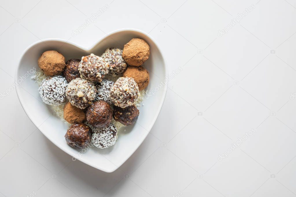 Homemade natural energy bites, vegan chocolate truffle with cacao on white. Healthy food for children, sweets substitute.