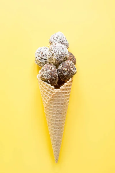 Palle energetiche fatte in casa in cono gelato e ingredienti per cucinare su fondo giallo. Sostituto di caramelle alimentari saporite sane . — Foto Stock