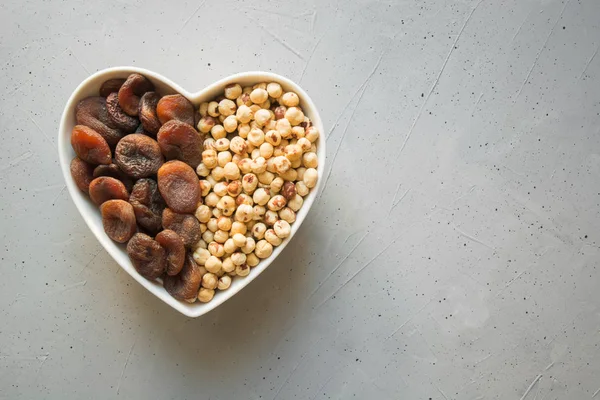 Dried organic apricots and hazelnut on grey concrete background. — Stock Photo, Image