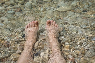 Kadın bacakları taşlı temiz deniz kenarında. Yaz tatili.