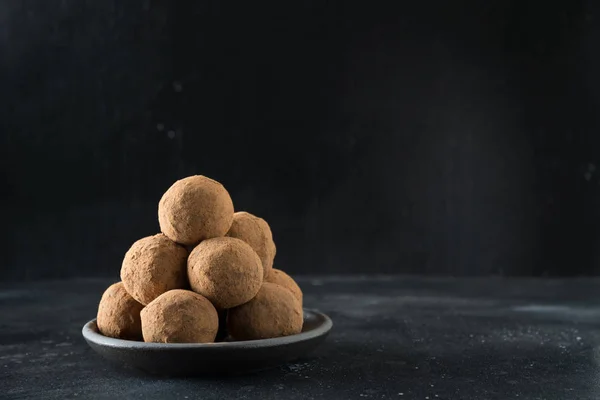 Bolas de energía caseras con cacao, coco sobre negro. Alimentos saludables para niños y veganos, sustitutos de los dulces . — Foto de Stock