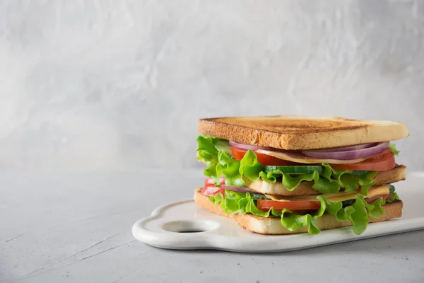 Sandwich with white toast bread, bacon, tomato, onion, salad, cheese on light. Space for text. — Stock Photo, Image