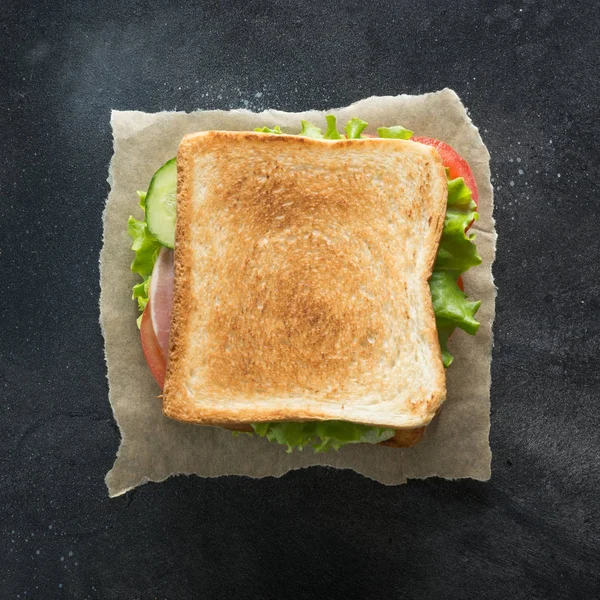 Sandwich with bacon, tomato, onion, salad on black background. — Stock Photo, Image