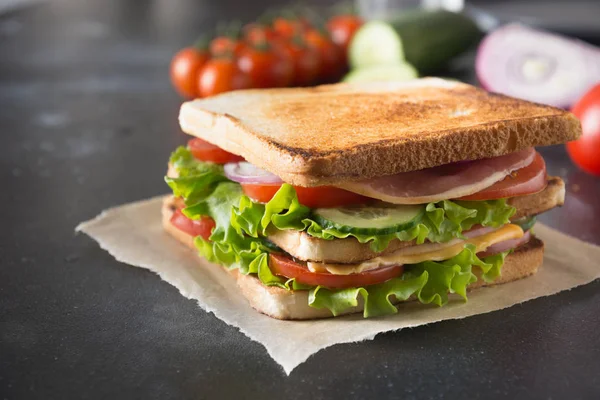 Sandwich with bacon, tomato, onion, salad on black. Close up. — Stock Photo, Image