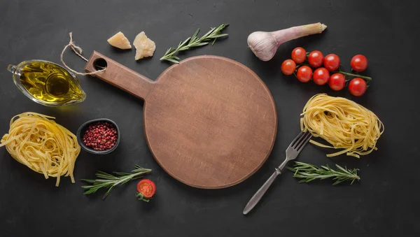 Határon száraz nyers tészta tagliatelle, paradicsom, bazsalikom, parmezán a főzés mediterrán ételeket. Szóköz a szöveghez. — Stock Fotó