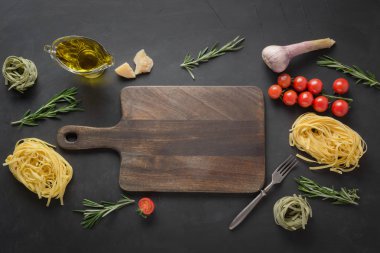 Kesme tahtası ve kuru ham makarna tagliatelle, domates, biberiye, parmesan sınır.