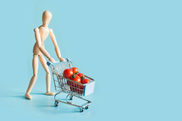 Buyer as wooden dolls with grocery trolley and tomatoes.