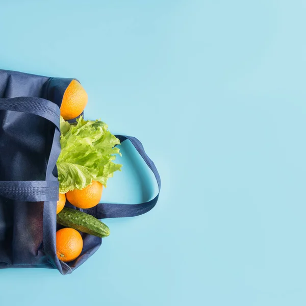 Zero waste concept. Blue shopping bag with orange and vegetables. Space for text.