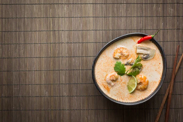 Tom yam kung pikante thailändische Suppe mit Garnelen, Meeresfrüchten, Kokosmilch, Chilipfeffer auf Matte. — Stockfoto