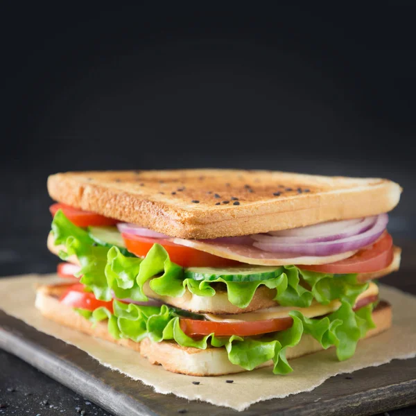 Sandwich with bacon,tomato, onion, salad on black background. — Stock Photo, Image