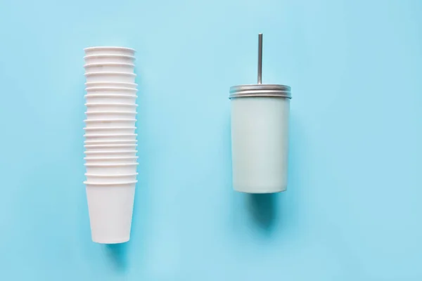 Montón de vasos blancos desechables uso semanal y taza reutilizable contrapeso para bebidas uso diario sobre fondo azul. Cero residuos. Libre de plástico . — Foto de Stock
