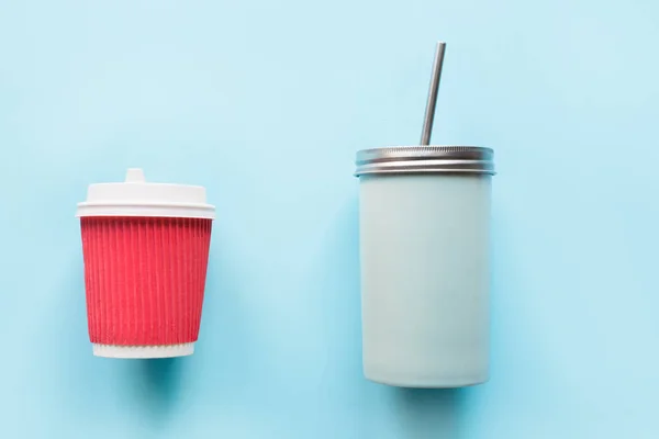 Disposable paper red cup and reusable mug on blue. Flat lay, top view. Concept zero waste and save our planet.