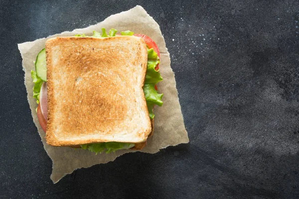 Sandwich with bacon, tomato, onion, salad on black background. — Stock Photo, Image