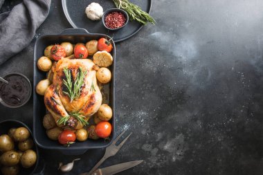 Patatesli kızarmış tavuk, siyah masada domates. Metin için boşluk. Yatay yönlendirme.