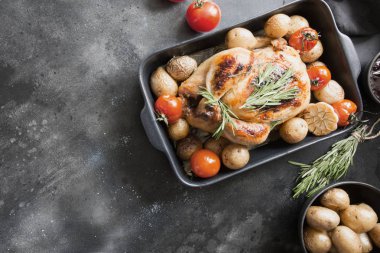 Patates ile kavrulmuş tavuk, siyah masada soslar ve şarap ile domates.