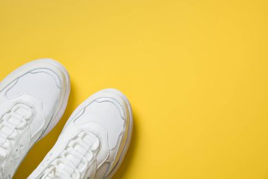 Sarı renkli beyaz kadın spor ayakkabıları. Düz döşeme, üst görünüm minimal arka plan.