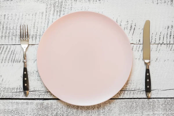 Налаштування столу з рожевою тарілкою на білому дерев'яному столі. Вид зверху . — стокове фото