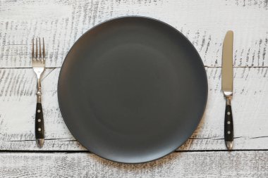 Beyaz ahşap masa üzerinde siyah plaka ile masa yeri ayarı. Üstte görüntü.