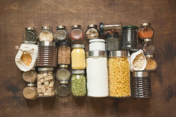 Homemade set of wholegrain cereals, pasta, spices, coffee, flour, sugar on a wooden tabletop. View from above.