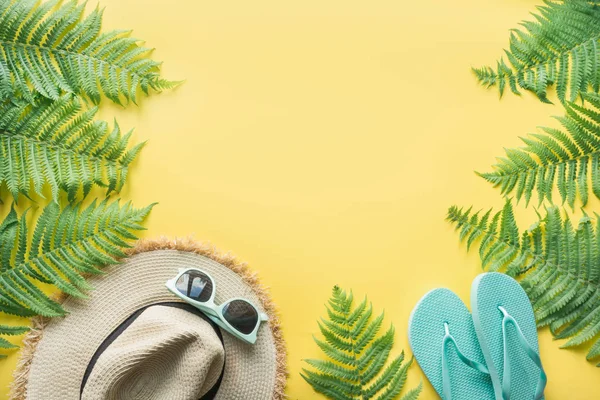 Strohhut, Sonnenbrille, Flip-Flops auf Gelb. Ansicht von oben. Sommerreisekonzept. — Stockfoto