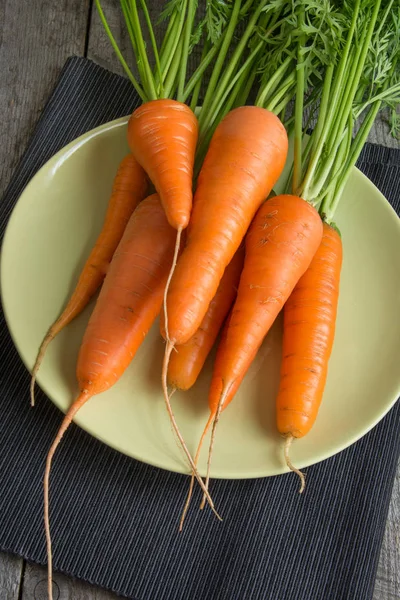 Zanahoria orgánica fresca en plato verde en la mesa rústica . — Foto de Stock
