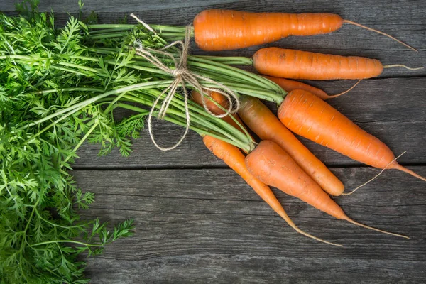 Zanahorias orgánicas frescas con tapas verdes y torzal en la mesa. Copiar espacio. Vista superior . — Foto de Stock