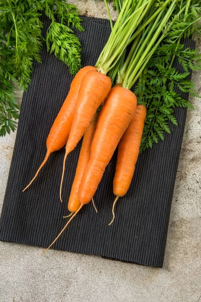 Zanahorias orgánicas frescas con tapas verdes en mesa rústica . — Foto de Stock