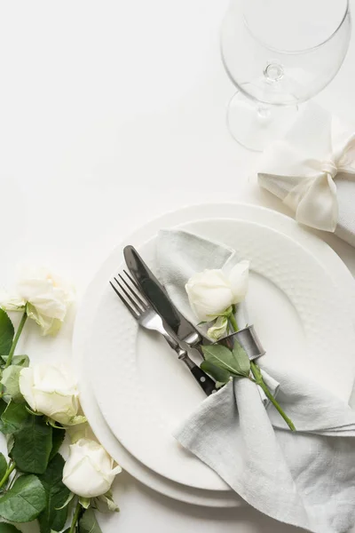 Configuração de mesa romântica e de casamento com rosa branca, presente, louça, prataria na mesa branca. Vista de cima . — Fotografia de Stock