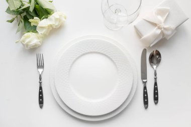 Buket gül, hediye, bulaşık, tatil beyaz masada gümüş ile beyaz masa ayarı. Yukarıdan görüntüleyin. Romantik ve evlilik yıldönümü.