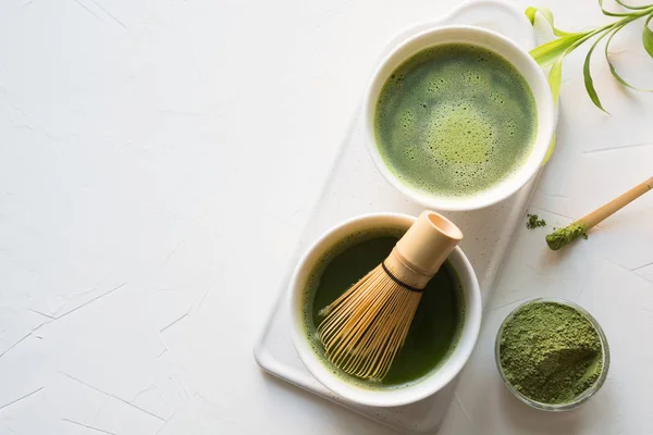 仪式绿色火柴茶和竹搅拌在白色的混凝土桌子上。顶部视图. — 图库照片