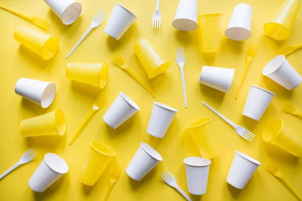 Einweg-Picknickutensilien auf gelb. umweltfreundlicher weggeworfener Plastikmüll für Recyclingkonzepte. flache Lage. — kostenloses Stockfoto
