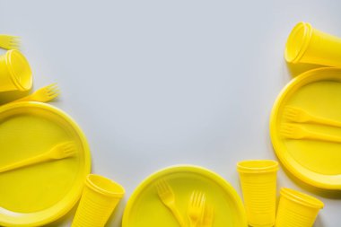 Tek kullanımlık piknik sarı mutfak eşyaları, tabaklar, bardak, gri çatal. Üst te. Metin için alan.