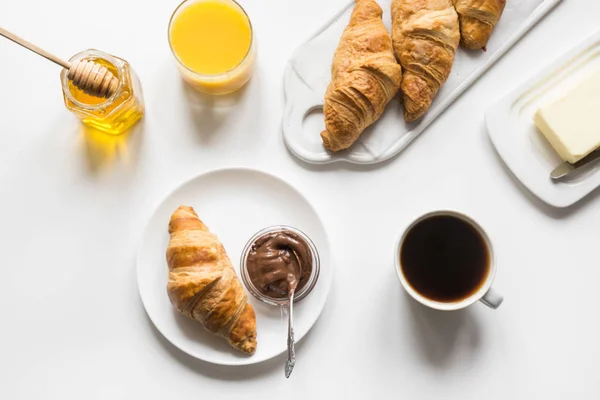 Croissants fraîchement cuits et tasse de café sur blanc. Espace pour le texte. Petit déjeuner français . — Photo