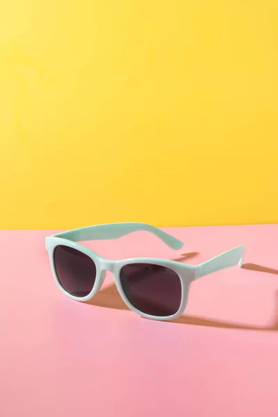 太阳眼镜，在创造性的黄色和粉红色背景上带有阴影。特写夏季概念. — 图库照片