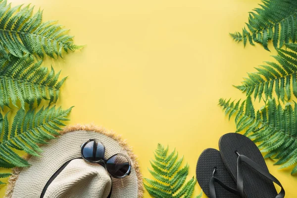 Strohhut, Sonnenbrille, schwarze Flip-Flops auf Gelb. Ansicht von oben. Sommerreisekonzept. — Stockfoto