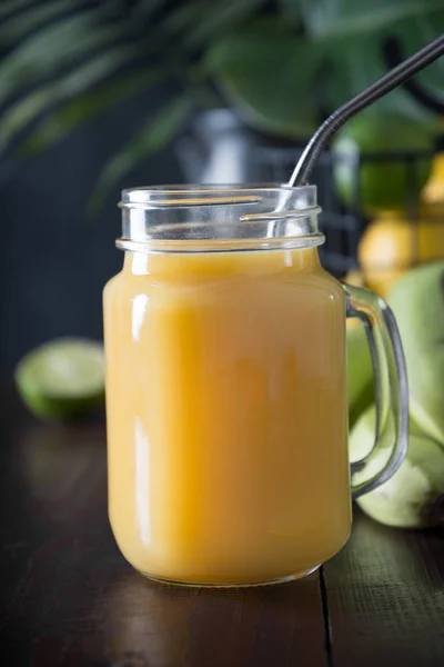 Fresh summer fruits smoothies with banana, lime on dark tropical wooden background. Close up. — Stock Photo, Image