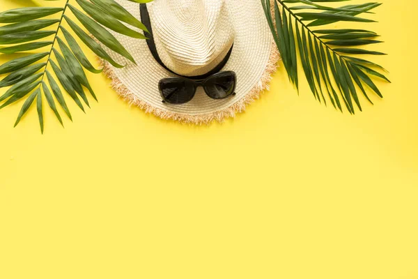 Сонячна солома пляжний капелюх з окулярами та тропічною долонею на жовтому. Концепція літніх канікул. Вид зверху — стокове фото