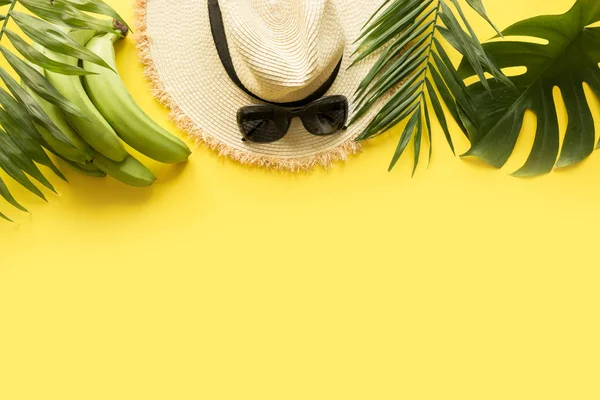 Sun straw beach hat with eyeglasses and tropical palm on yellow. Summer vacations concept. Top view — Stock Photo, Image