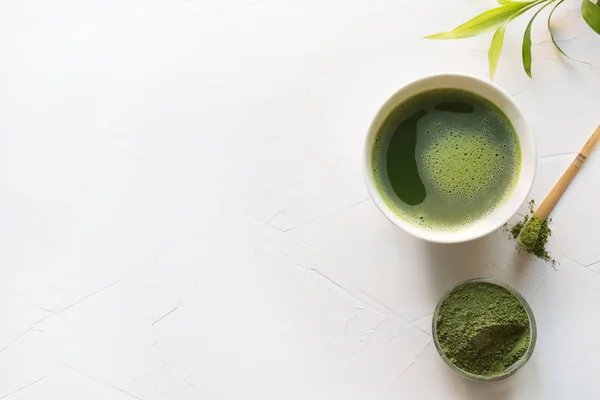 Green matcha tea and bamboo whisk on white concrete table. Top view. Copy space. — Stock Photo, Image