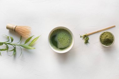 Tören yeşil matcha çay ve bambu çırpıcı beyaz beton masada. Üstte görüntü.