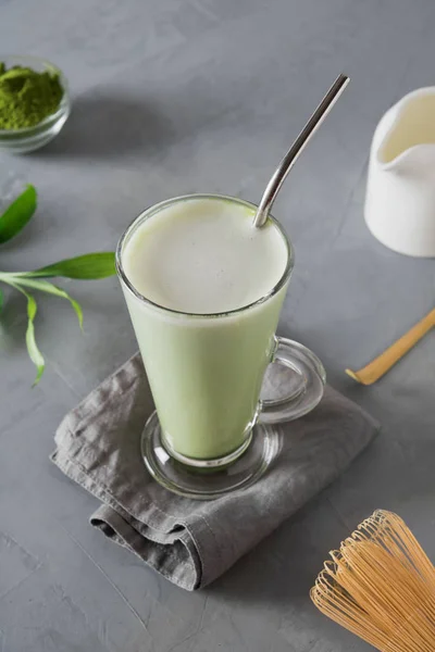 绿色冷火柴茶配牛奶,冰块在拿铁玻璃灰色桌子上。特写从上面查看. — 图库照片