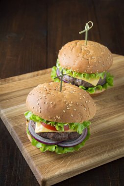 Tahta tahtada sebzeli taze iki sığır burgeri. Parti. Dikey yönlendirme.