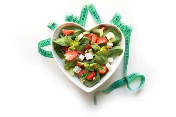 Fresh salad of strawberry, celery, spinach, pine nuts, cheese in plate as heart on white. Concept clean eating for Detox. — Stock Photo, Image