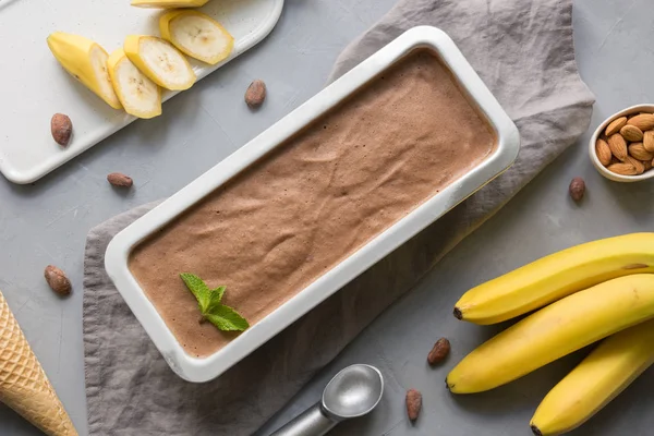 Chocolate de plátano helado casero en recipiente con granos de café en gris. Espacio para texto.Vista superior . — Foto de Stock