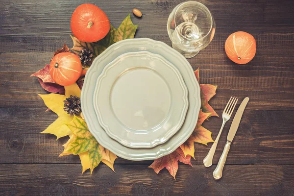 Cenário de mesa de outono e dia de Ação de Graças com folhas caídas, especiarias, prato cinza e prataria na mesa de madeira. Vista superior . — Fotografia de Stock